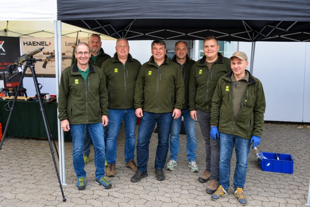 Das Team von Waffen Geus bei der Hausmesse: sieben Männer in grünen Fleecejacken unter einem Zelt.